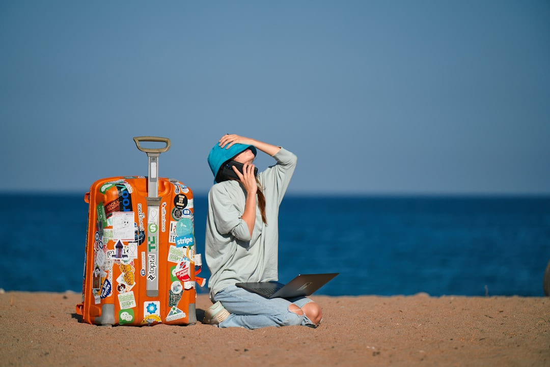 a person sitting on a beach with a suitcase and a laptop on The Anywhere Office