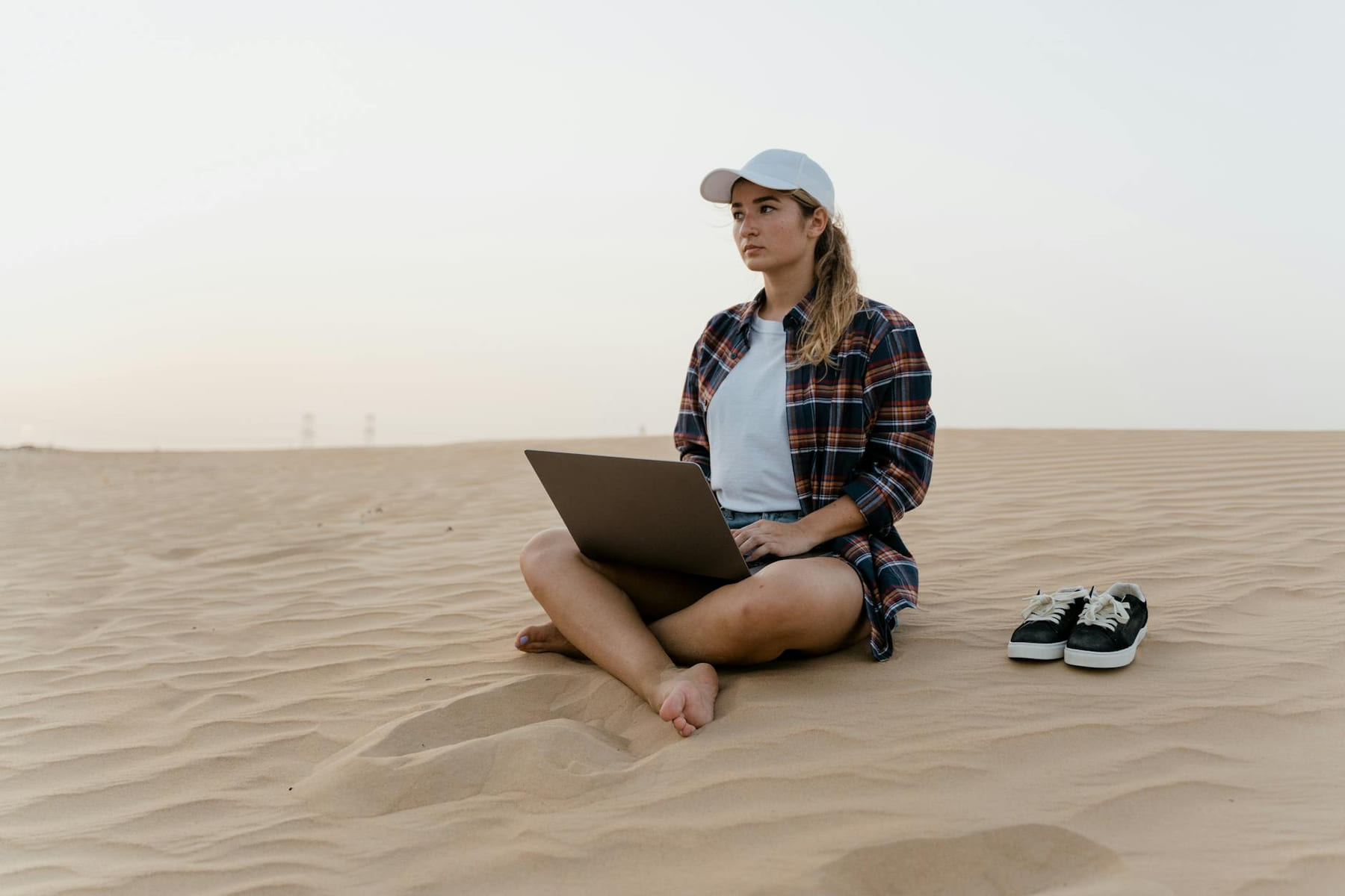 A woman working on a laptop in the desert. Ideal for remote work and travel themes. on The Anywhere Office