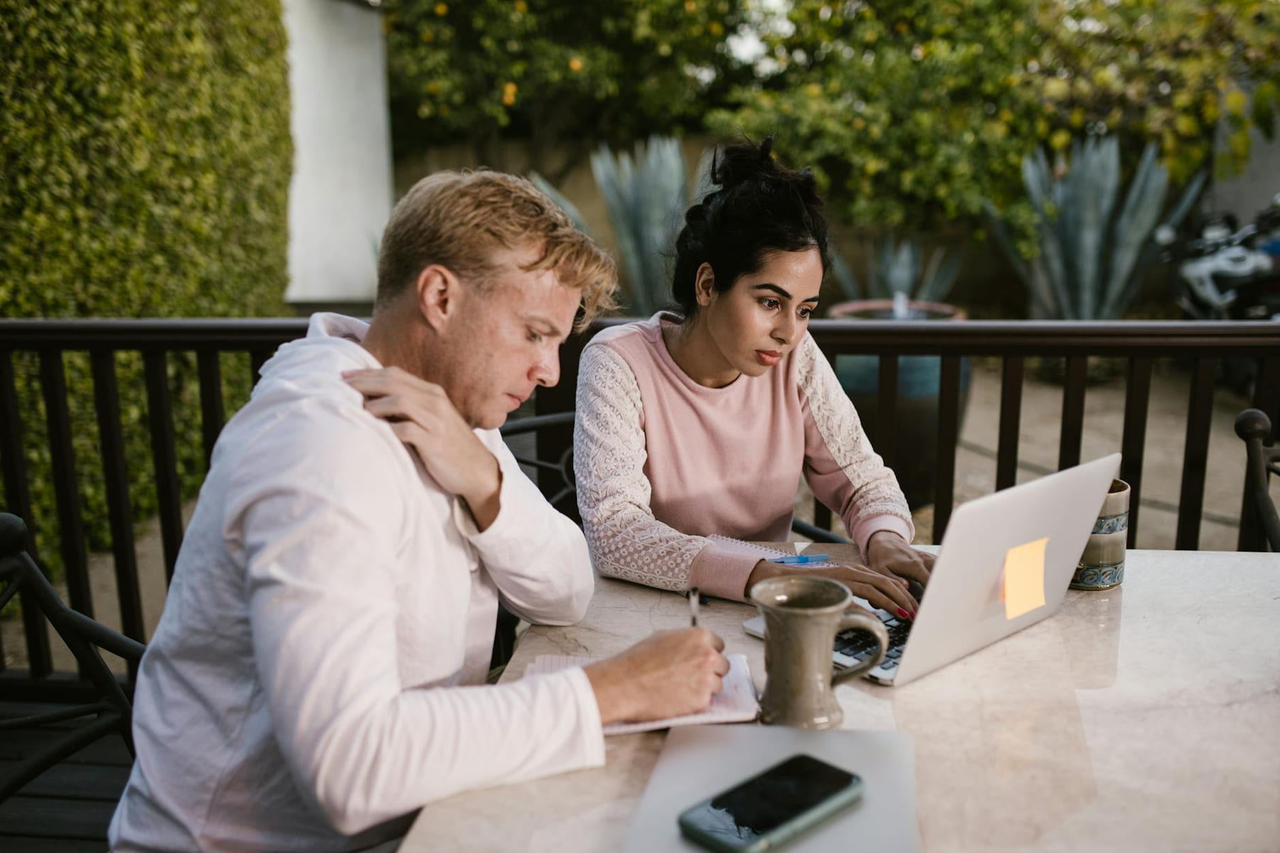 Two adults working together on a laptop outdoors, focusing on a project. on The Anywhere Office
