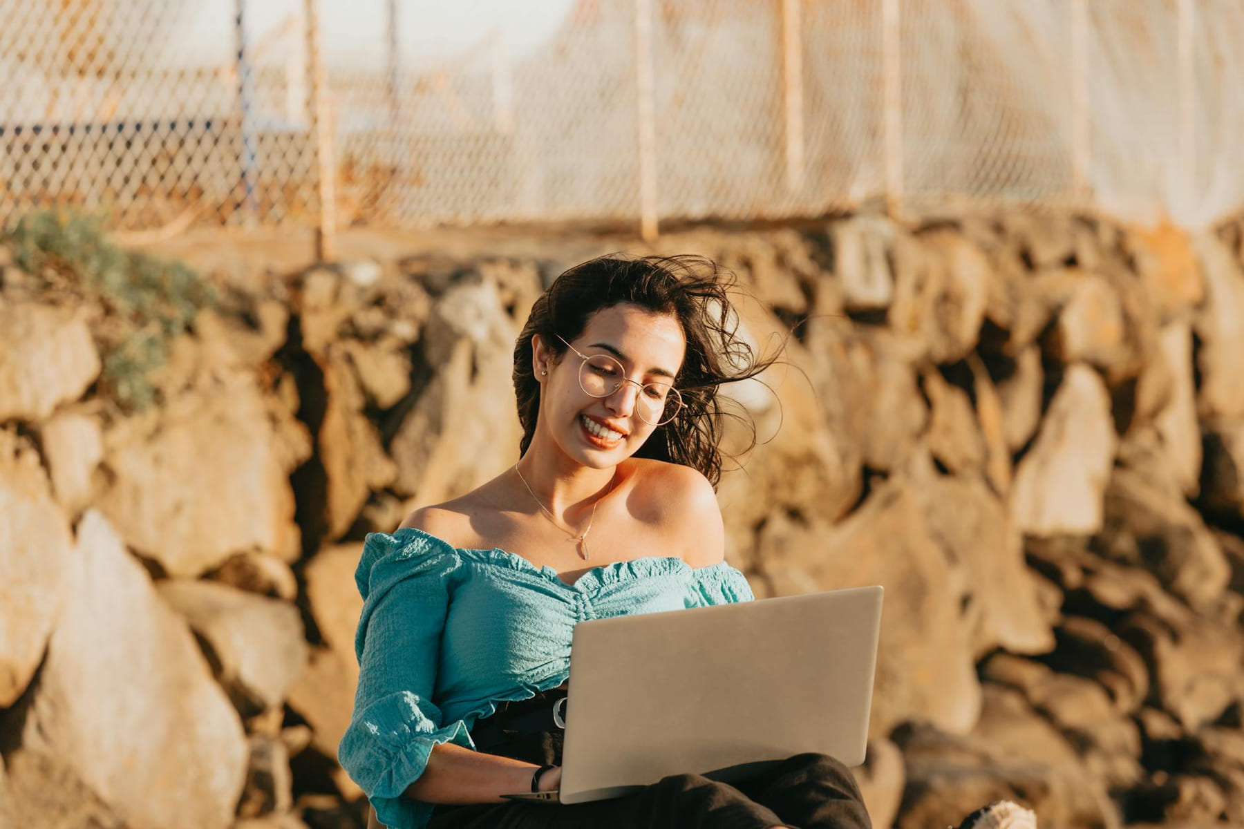 Woman enjoying remote work with laptop outdoors, smiling on a windy day. on The Anywhere Office
