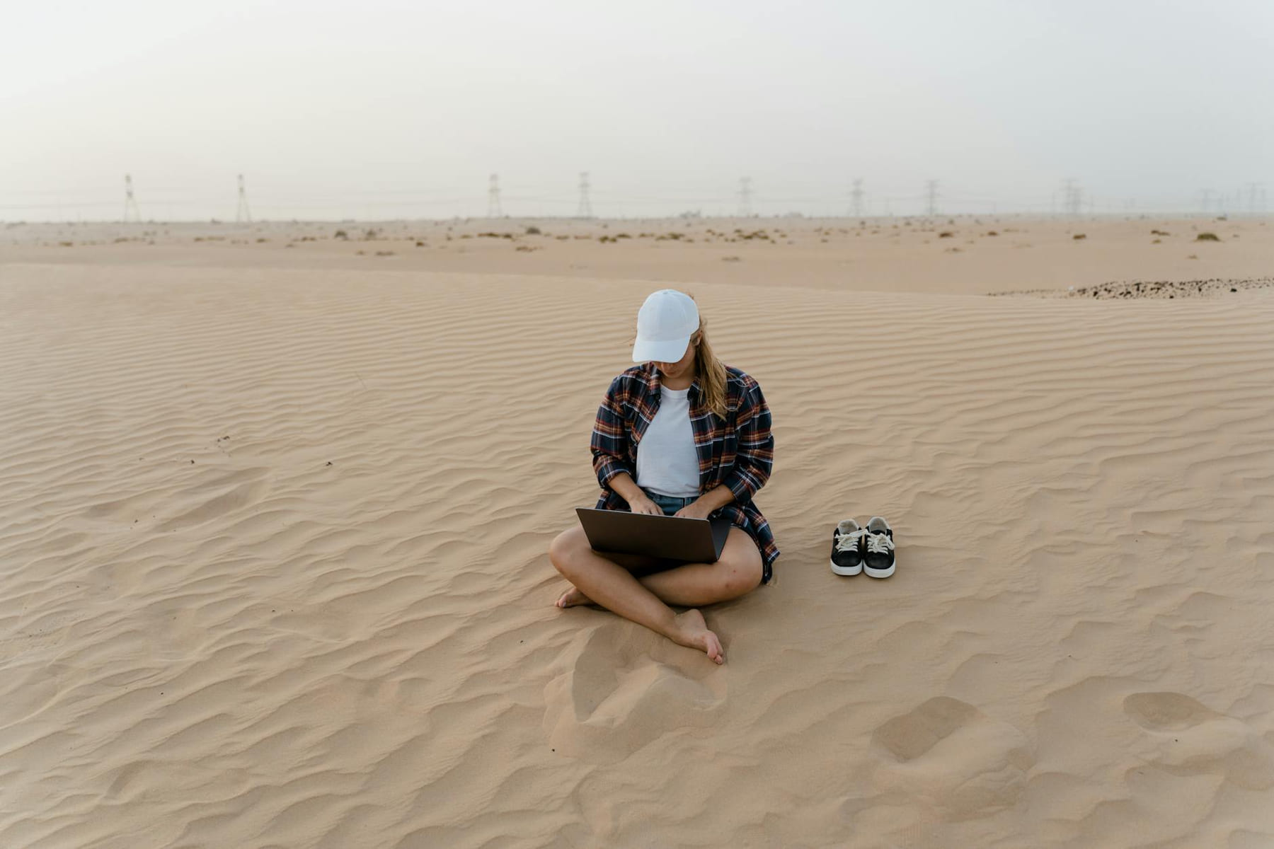 A woman in a desert using a laptop, symbolizing remote work freedom and digital nomad lifestyle. on The Anywhere Office