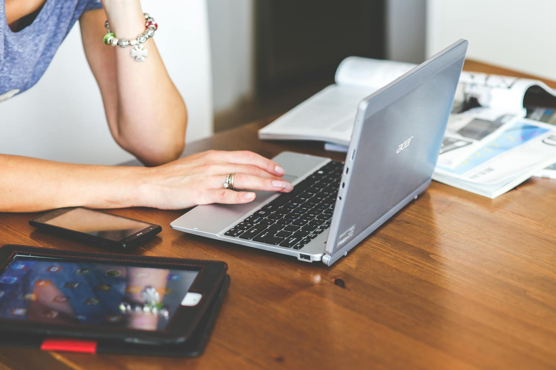 Woman working remotely on a laptop with mobile devices on a wooden desk. on The Anywhere Office