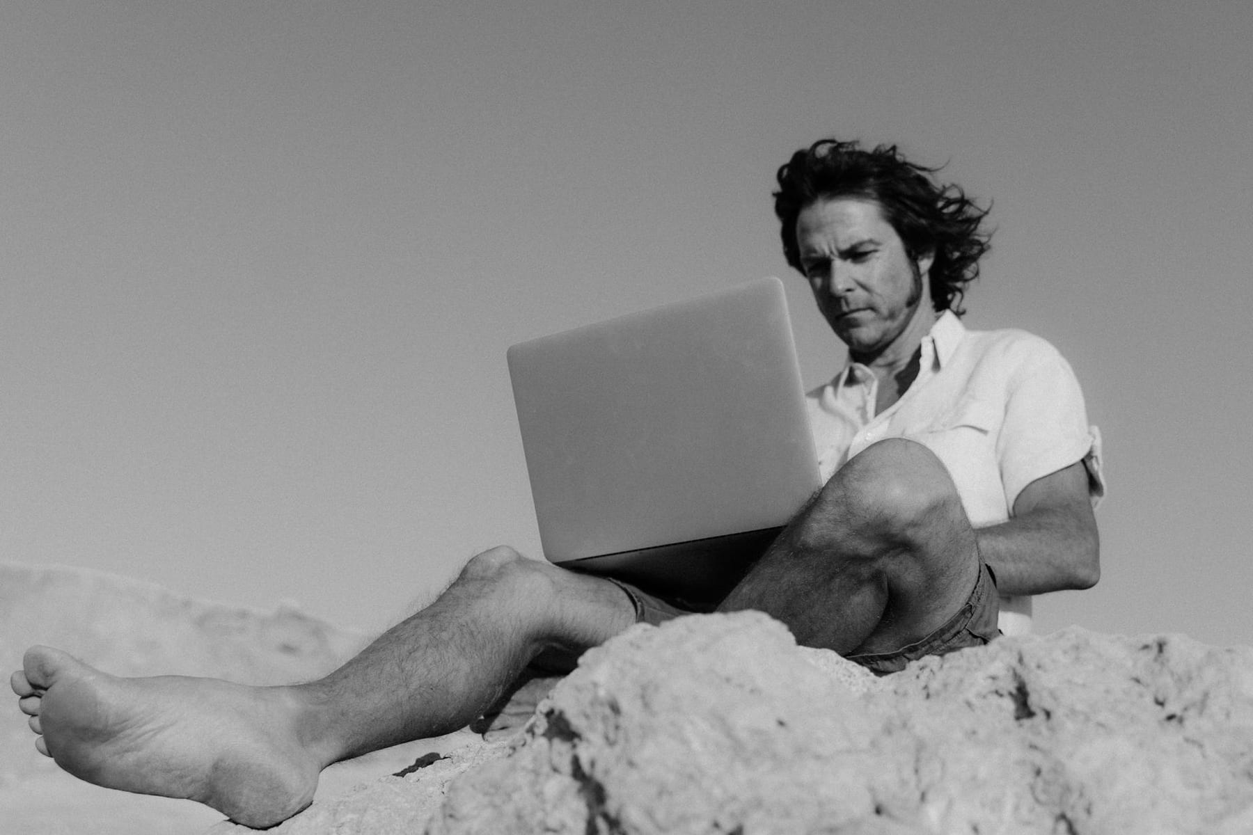 A man working remotely on a laptop outdoors, focused and serious. on The Anywhere Office