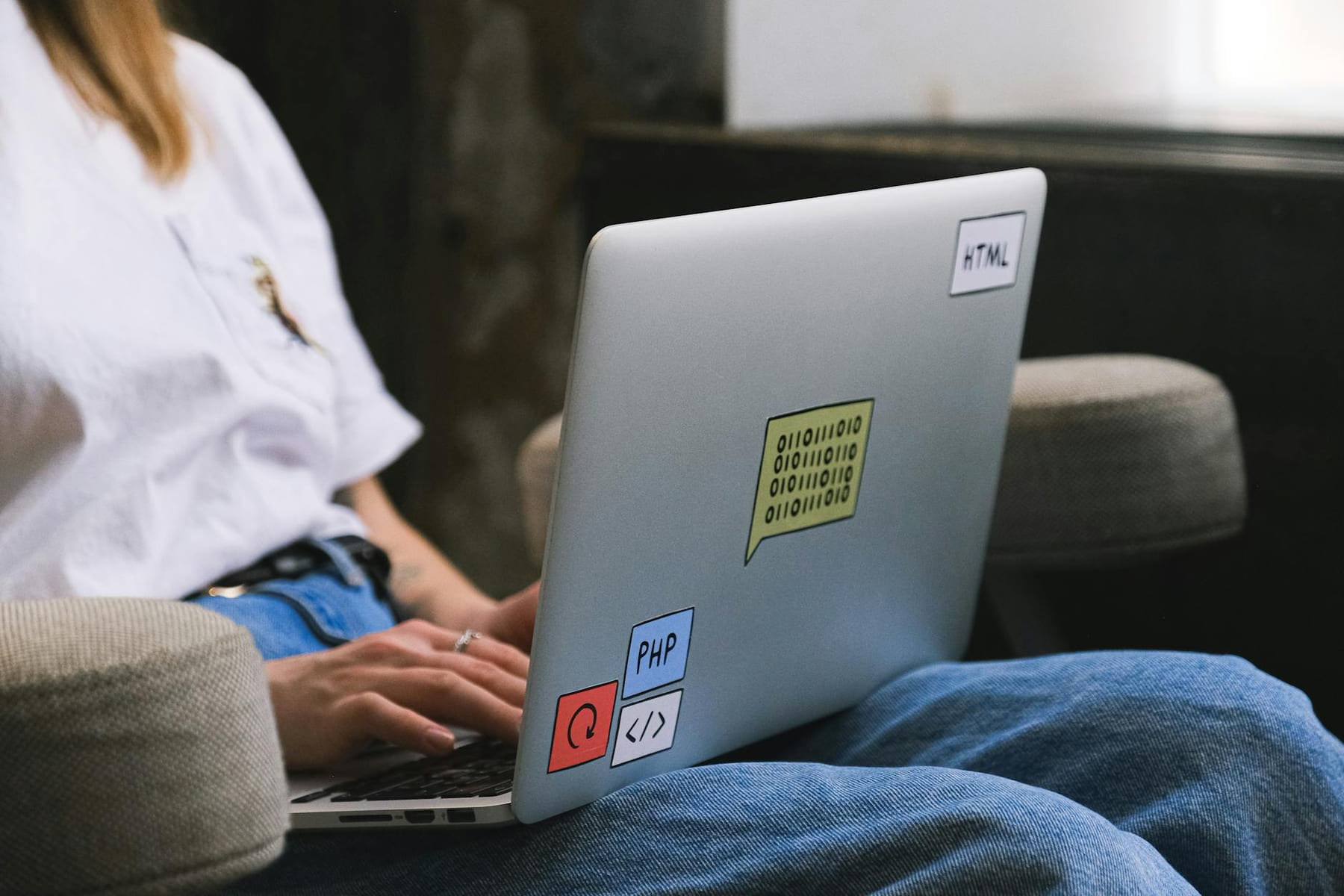 Person typing on a laptop with coding stickers, symbolizing remote work and freelancing. on The Anywhere Office