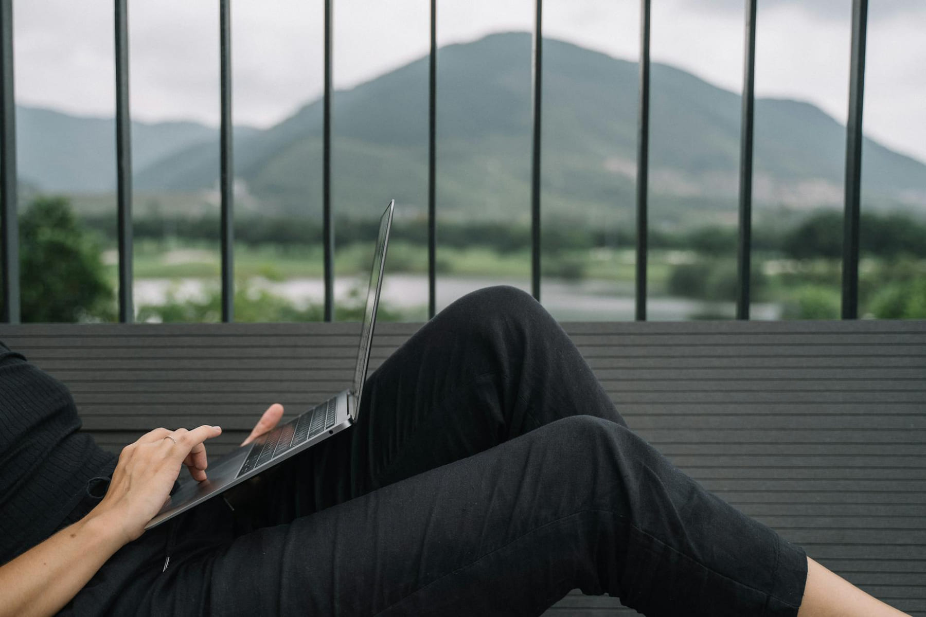 Person working remotely on a laptop, enjoying a serene mountain view from a balcony. on The Anywhere Office